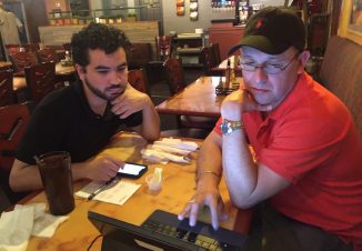 Graduate Hammurabi sits with Capital IDEA alum Heriberto, guiding his job search on a computer.