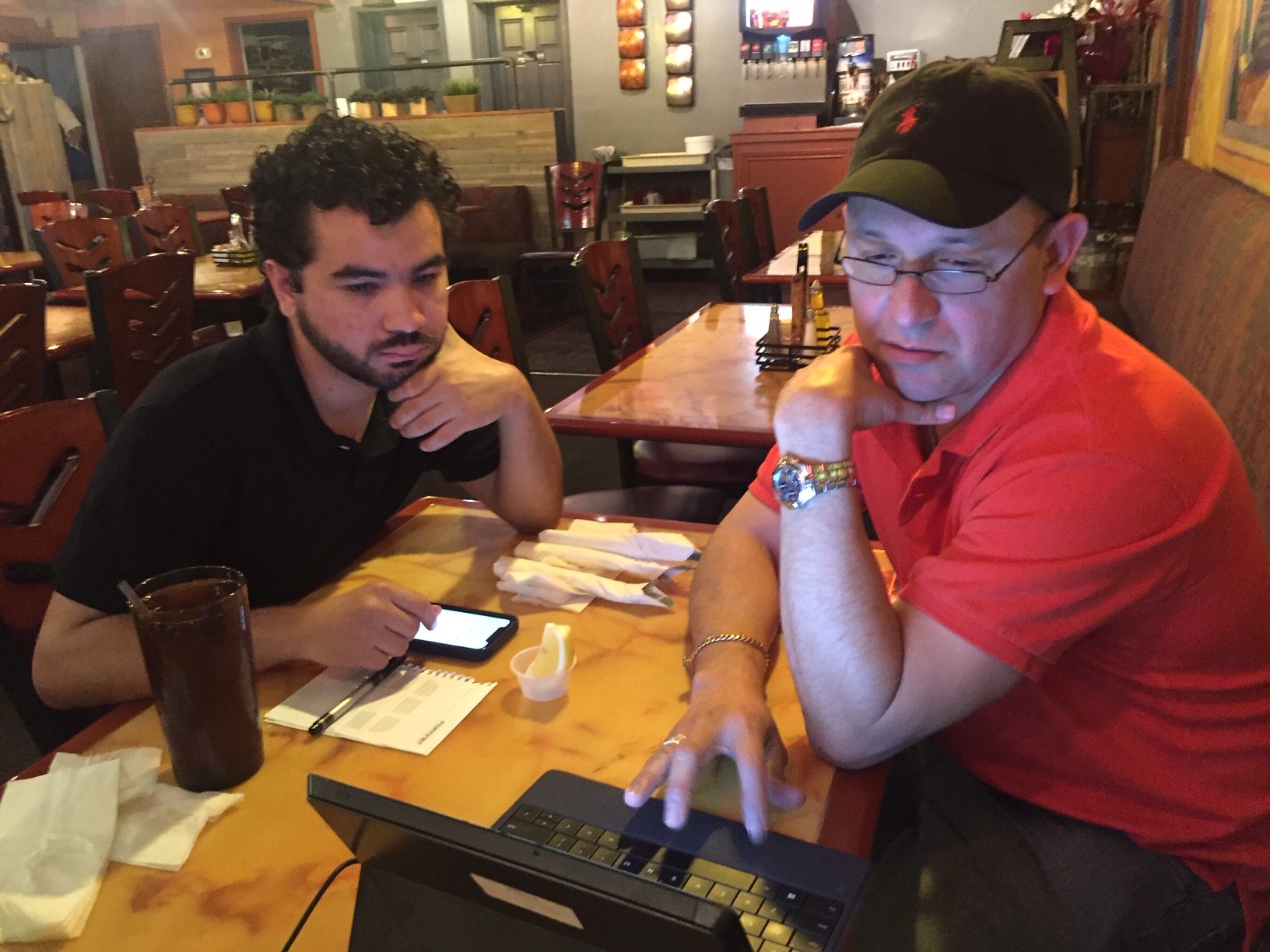 Graduate Hammurabi sits with Capital IDEA alum Heriberto, guiding his job search on a computer.